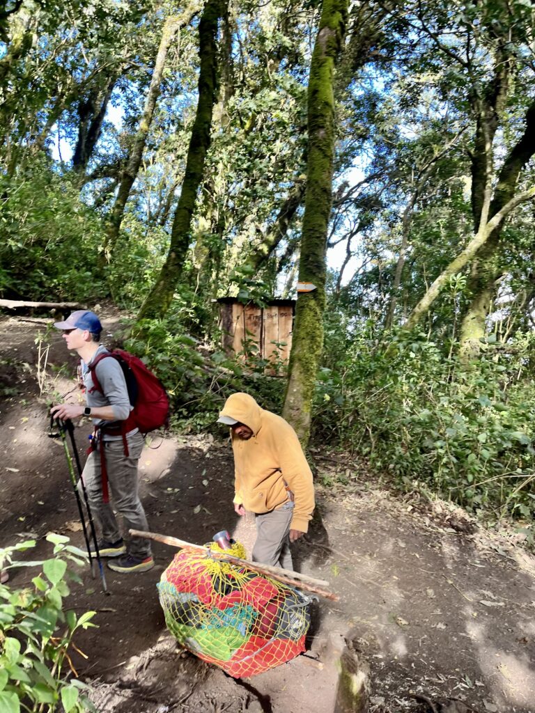 Hikers and porters converse on a trail.