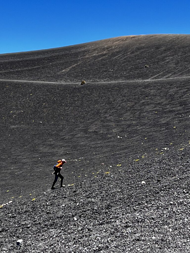 A lone hiker ascends the crater of a volcano.