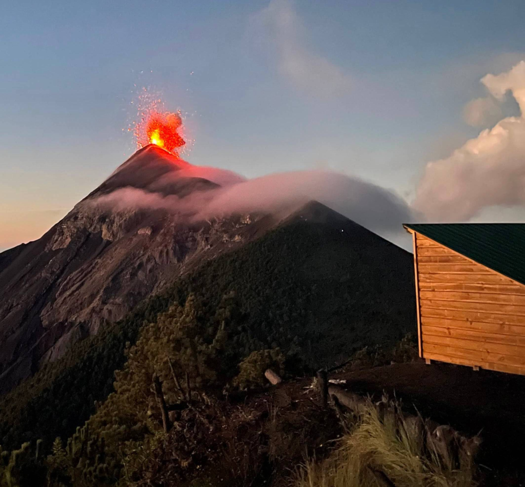A shelter facing the great mass of Volcán Fuego as it erupts.