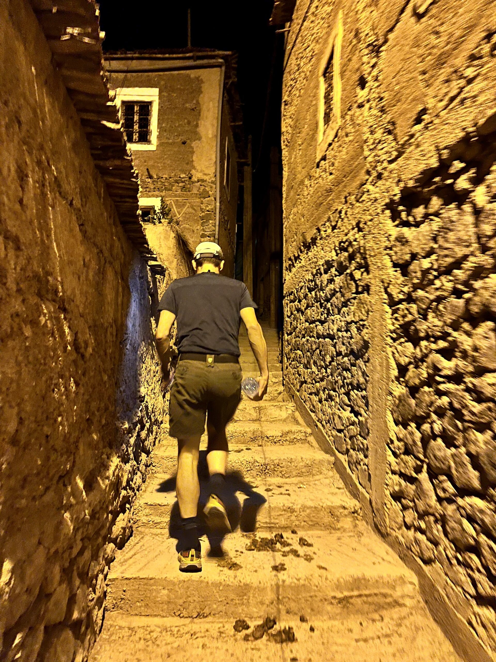 A man jogs between buildings in the dark.